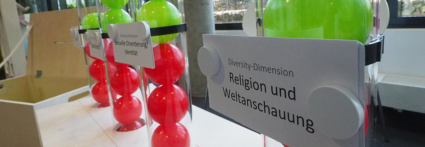 Gelbe und Rote Kugeln in einem Glasbehälter mit der Aufschrift Religion und Weltanschauung.
