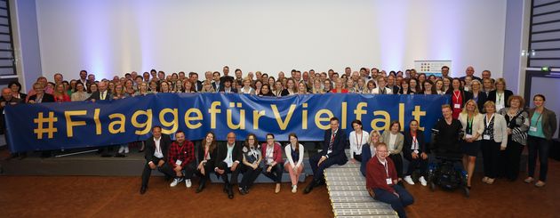 Gruppenfoto mit ca. 80 Personen des Diversity Netzwerk Rhein-Ruhr, die einen Banner halten, auf dem Hashtag Flagge für Vielfalt steht.