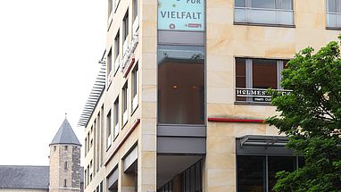 Auf den Fenstern eines Gebäudes sind der DDT Flyer und die Aufschrift Köln liebt Vielfalt abgebildet.